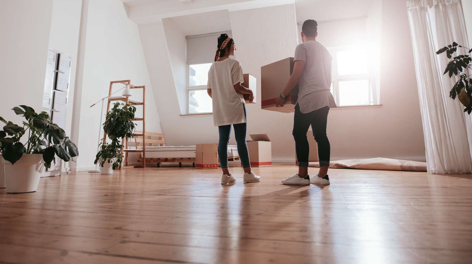 Jeune couple portant des cartons dans un appartement vide